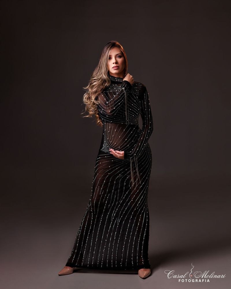 Gestante em vestido preto bordado de cristais, em estúdio