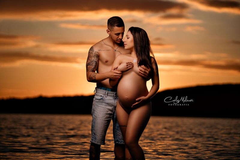 Casal ao pôr do sol na beira do lago