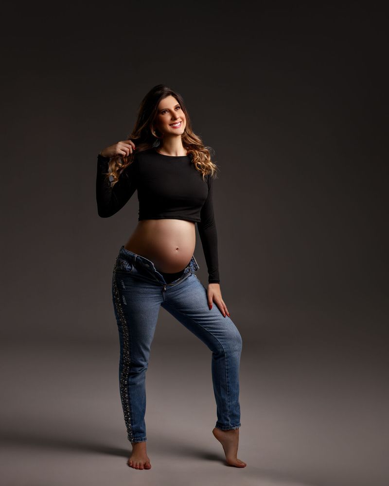 Gestante de blusa preta e jeans em estúdio