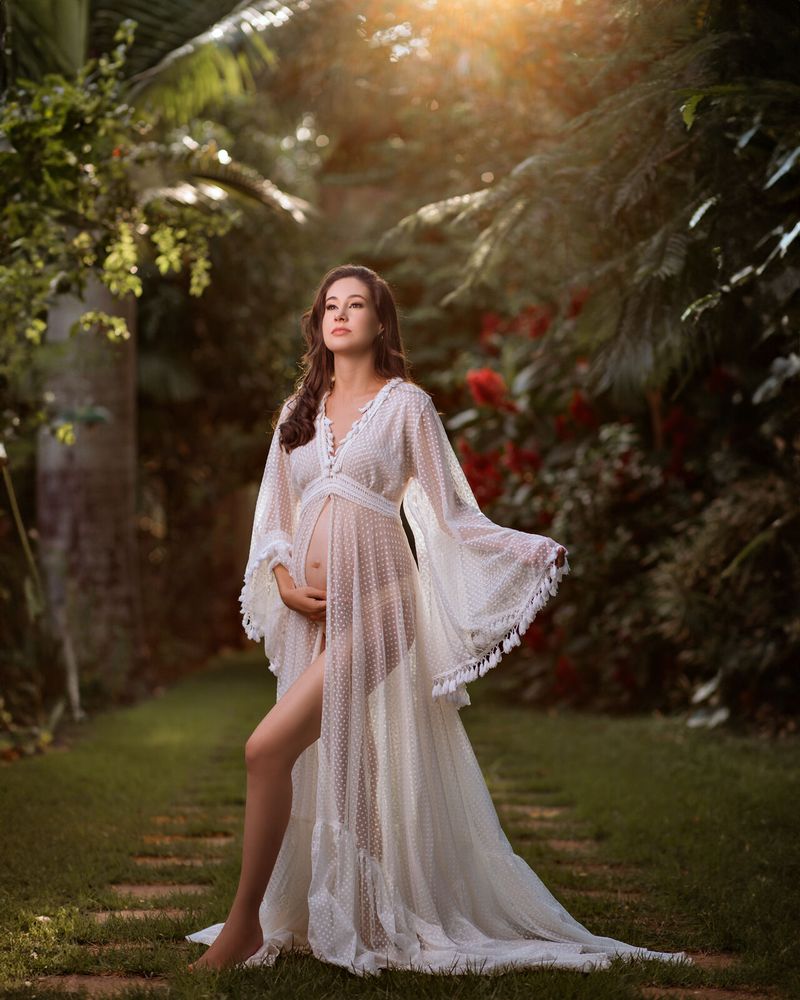 Gestante de vestido branco rendado em jardim