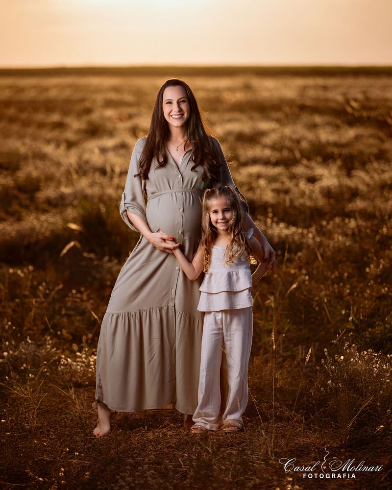 Gestante com a filha em campo ao entardecer