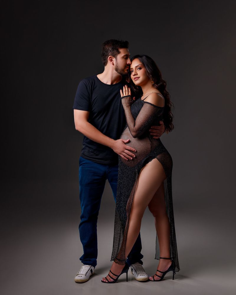 Casal em estúdio, ele abraçando a gestante