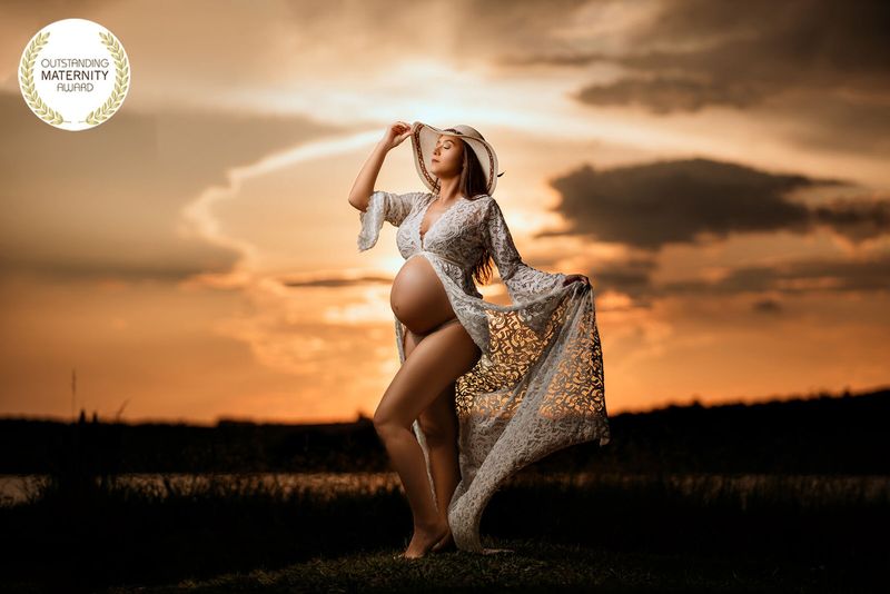 Gestante com vestido de renda ao pôr do sol, foto premiada