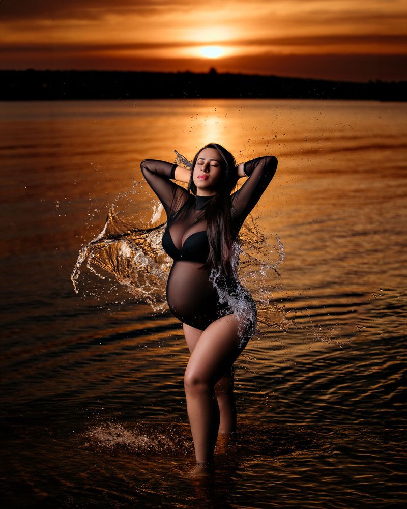 Gestante em ensaio splash na água, ao pôr do sol