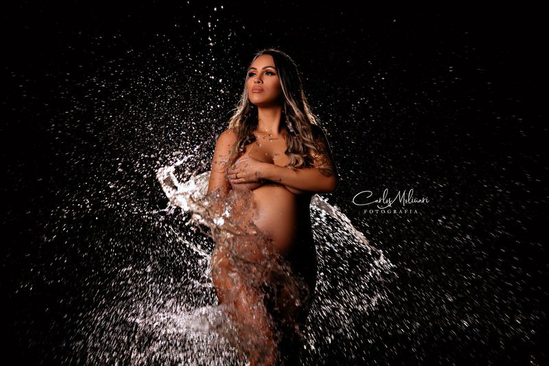 Gestante em splash de água em fundo preto